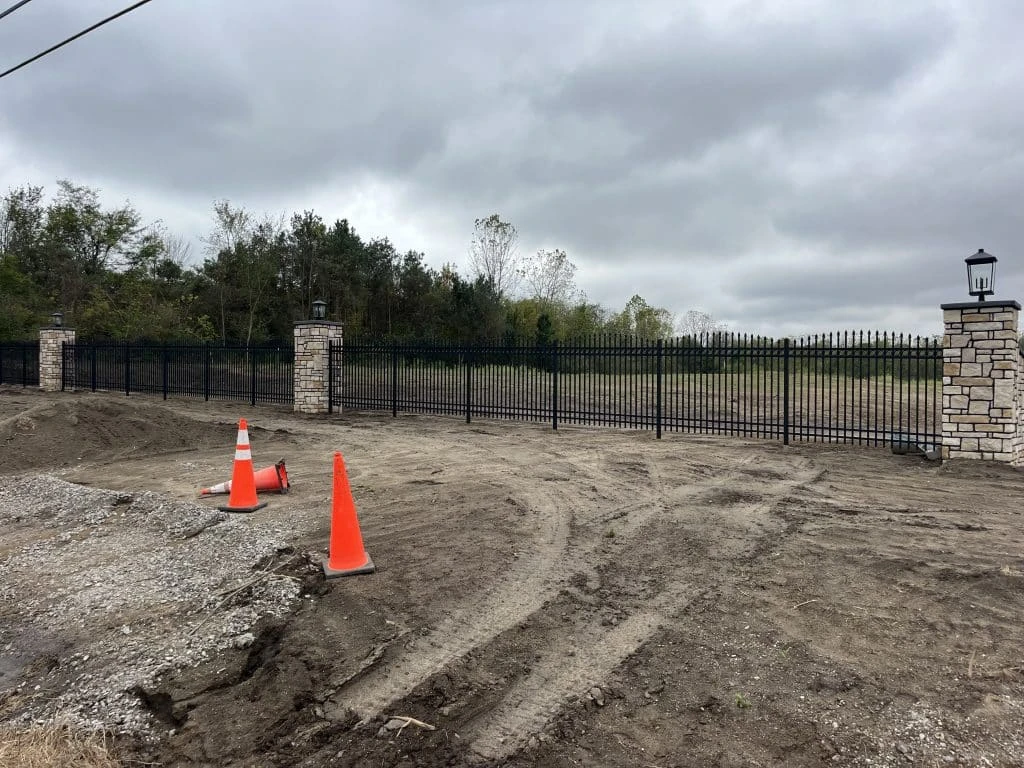 Ornamental black aluminum fence with stone columns and decorative post lights installed near Fort Wayne, Indiana