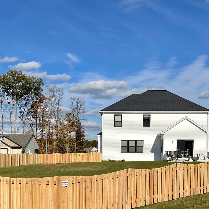 Roanoke fence company Custom wood privacy fence installation with a concave design surrounding a modern home