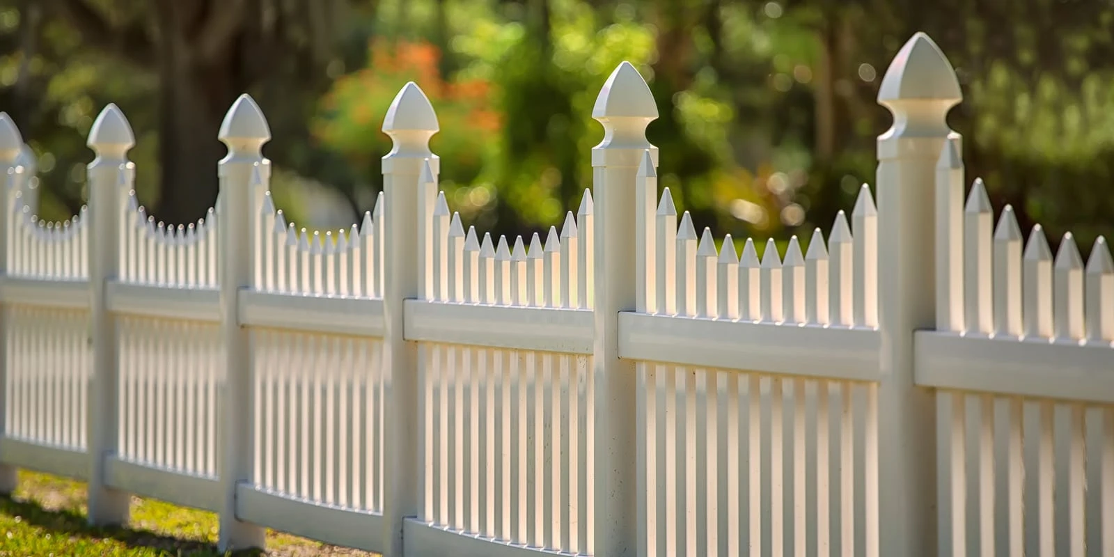 Close-up of a decorative white vinyl picket fence with cap and trim posts in Fort Wayne, Indiana