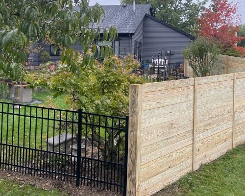 Custom horizontal wood privacy fence with ornamental black aluminum accent fence installed near Columbia City, Indiana backyard by Allen County Fence Company
